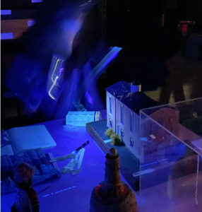 A conservator uses a special light to reveal substances not as easily seen under normal light. On the roof, a wax-like residue glows orange when illuminated, Fall 2021