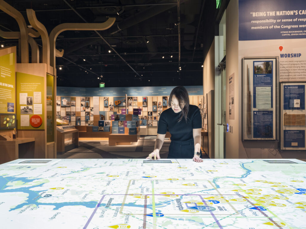 A woman with dark hair leans over a large lit up map of DC.