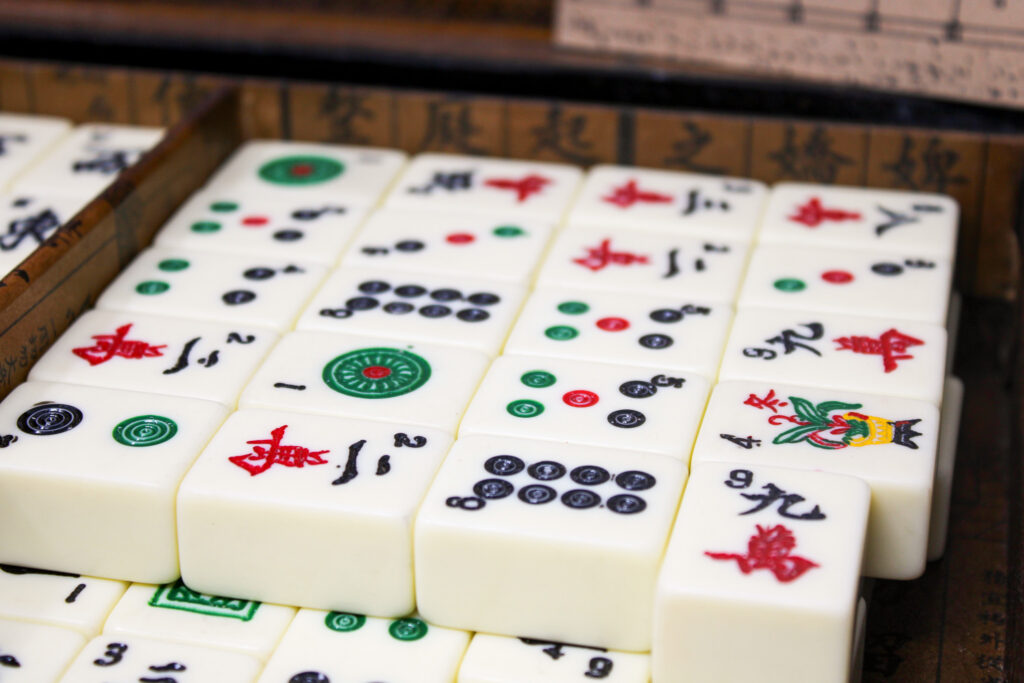 Photograph of mahjong tiles with different characters arranged in a wooden box.
